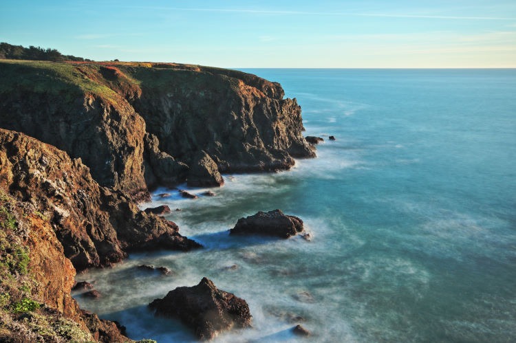Long exposure seascape photograph of sea cliffs bathed in evening light