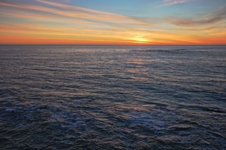Seascape photograph of the sun setting over the Pacific Ocean